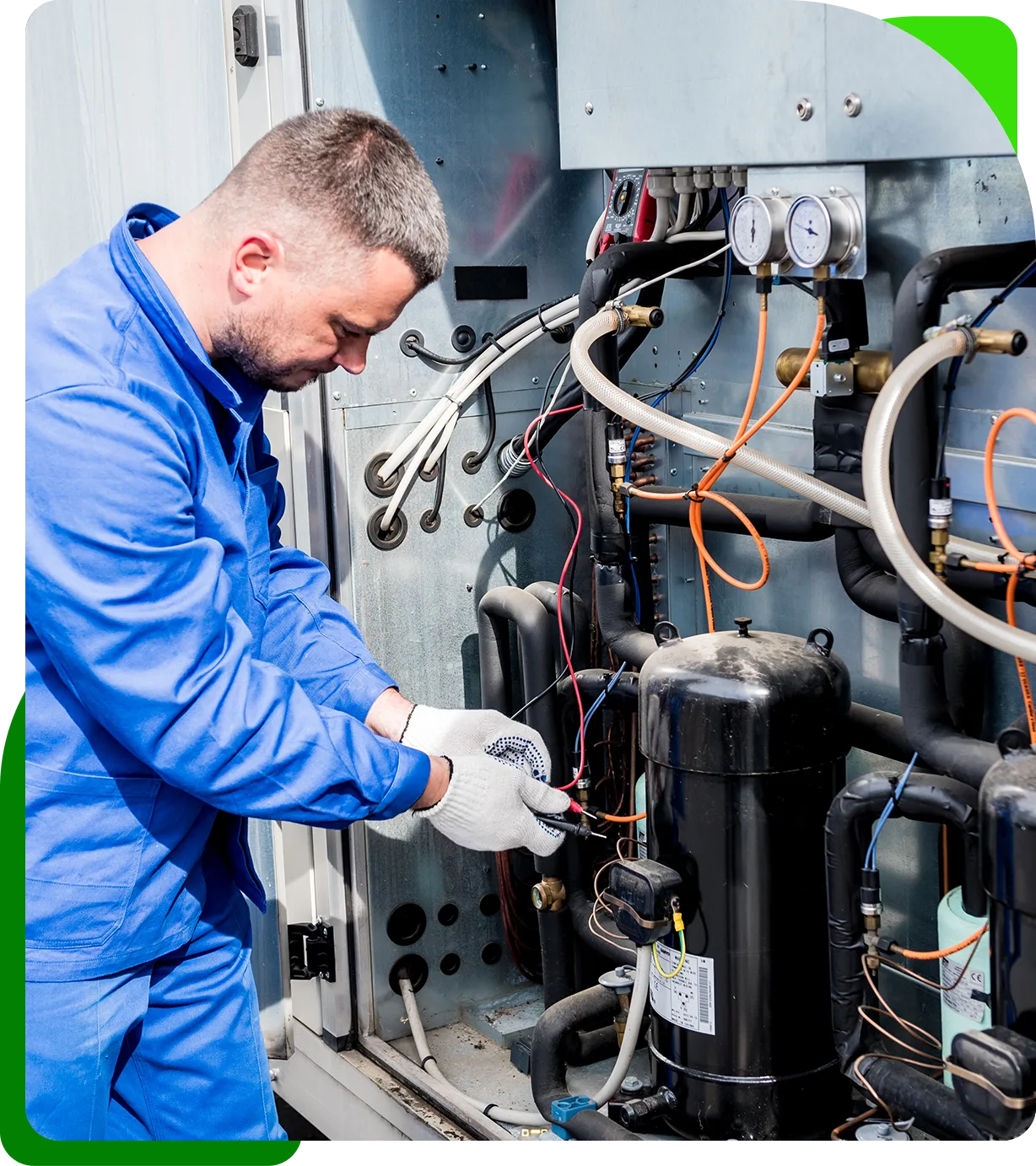 Technician in blue uniform repairs industrial equipment with wires and gauges visible, wearing protective gloves, working outdoors.